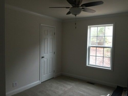 An empty room with a ceiling fan and a window