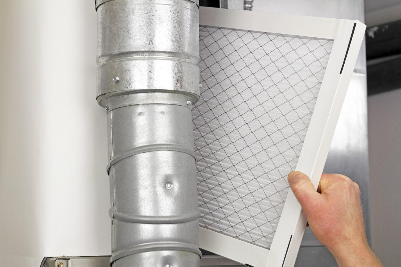 Person replacing air filter in silver ductwork.