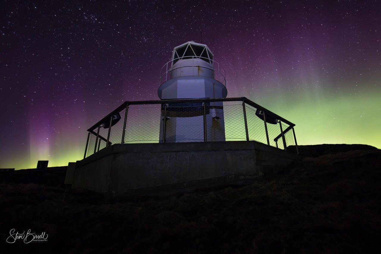 A lighthouse with a purple sky in the background