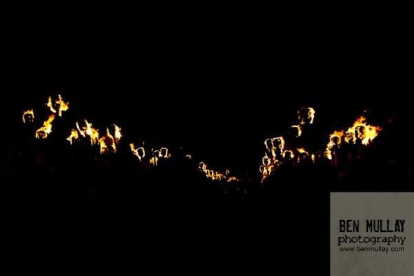 A bunch of candles are lit up in the dark.