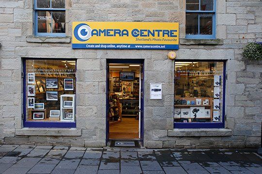 A store front with a yellow sign that says camera centre