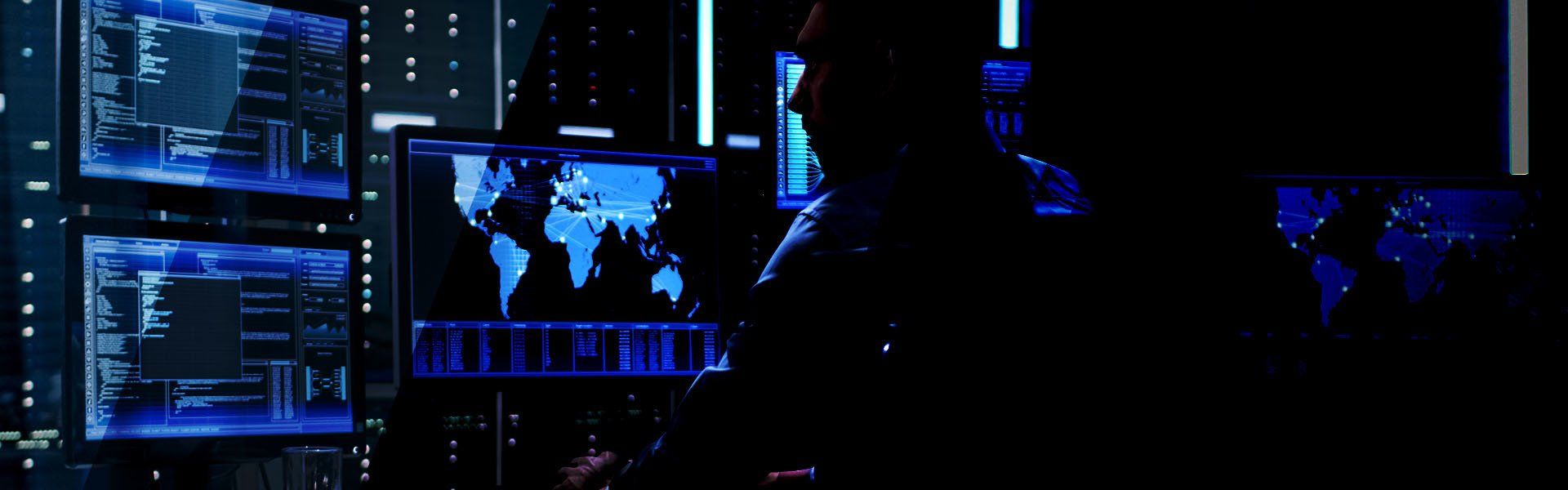 Dark control room with glowing blue monitors showing data charts, a world map, and code.