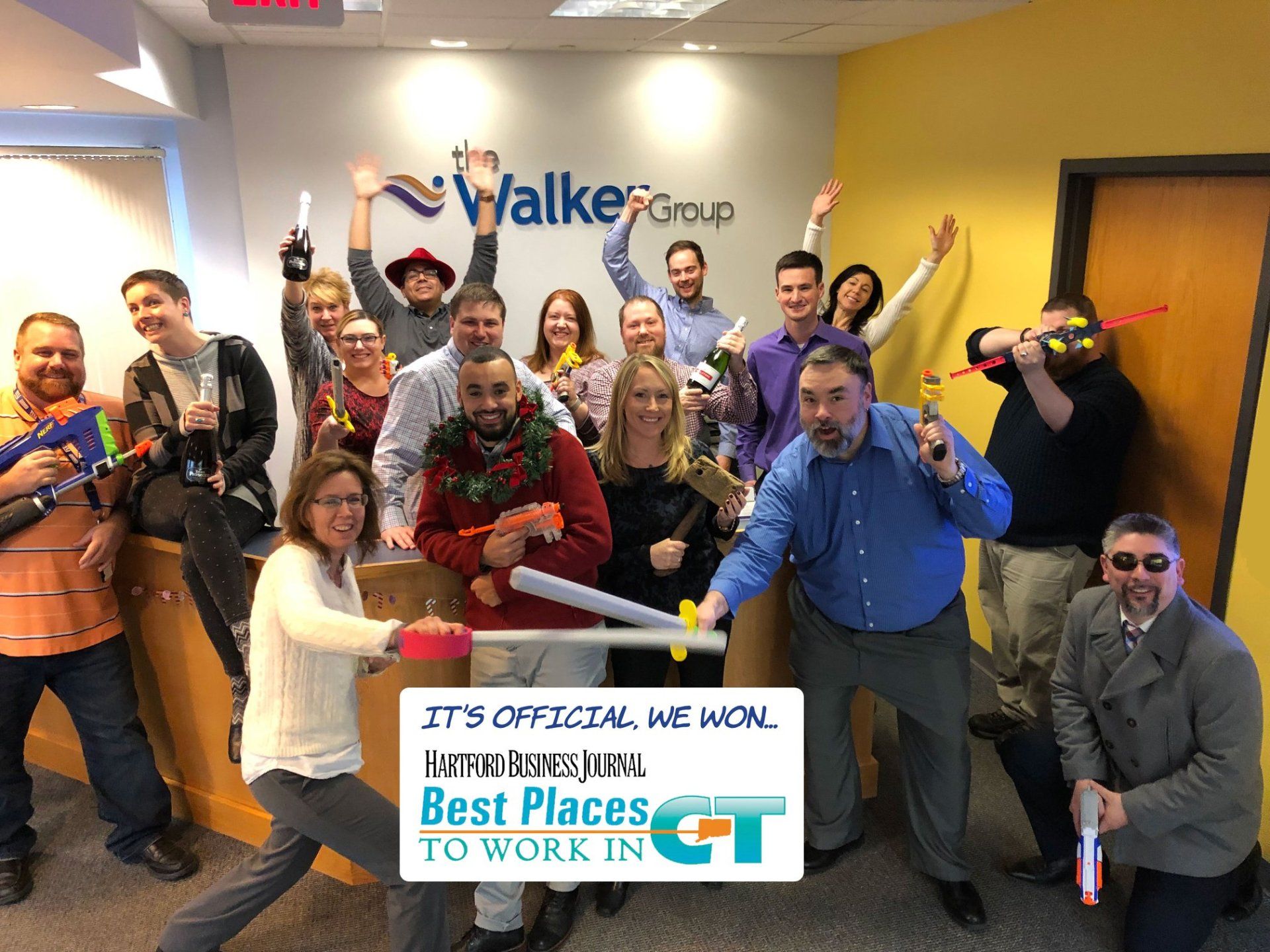 Group of people posing with a “Best Places to Work” award sign in a conference room, smiling and cheering