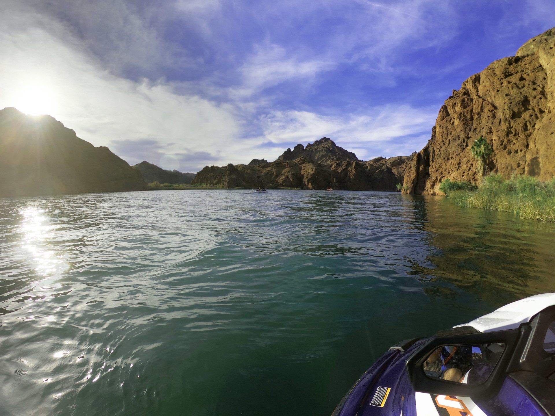 A person is riding a jet ski on a lake with mountains in the background.