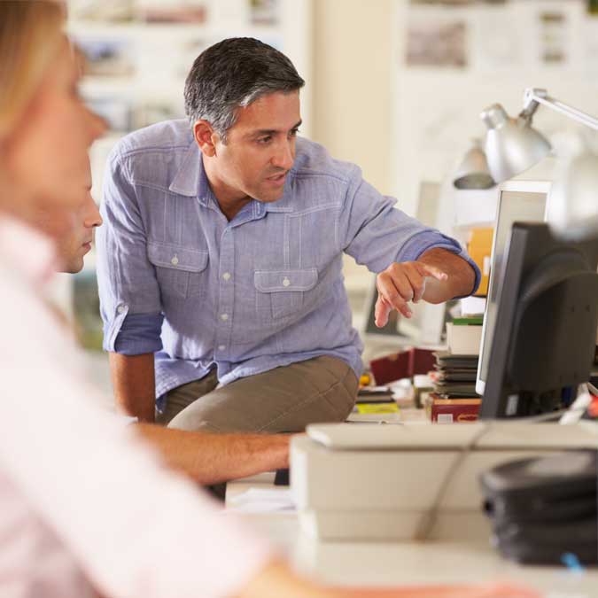 A man sitting at a desk looking at a computer screen