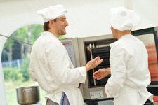 Two chefs are talking to each other in a kitchen.