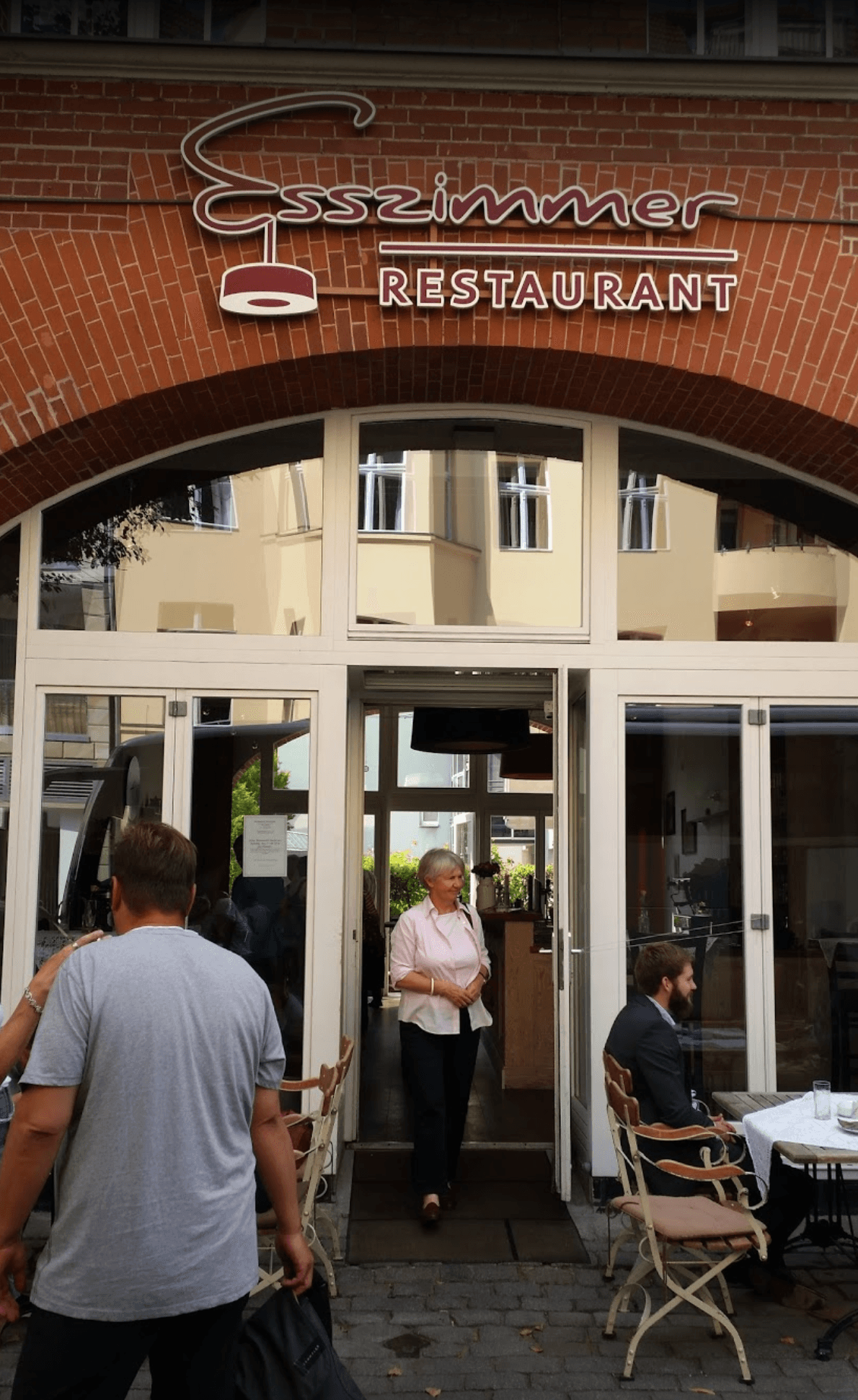 A group of people are standing outside of a restaurant.