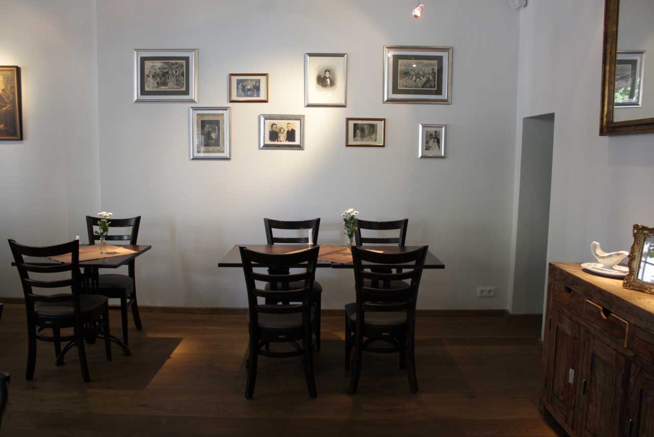 A dining room with tables and chairs and pictures on the wall