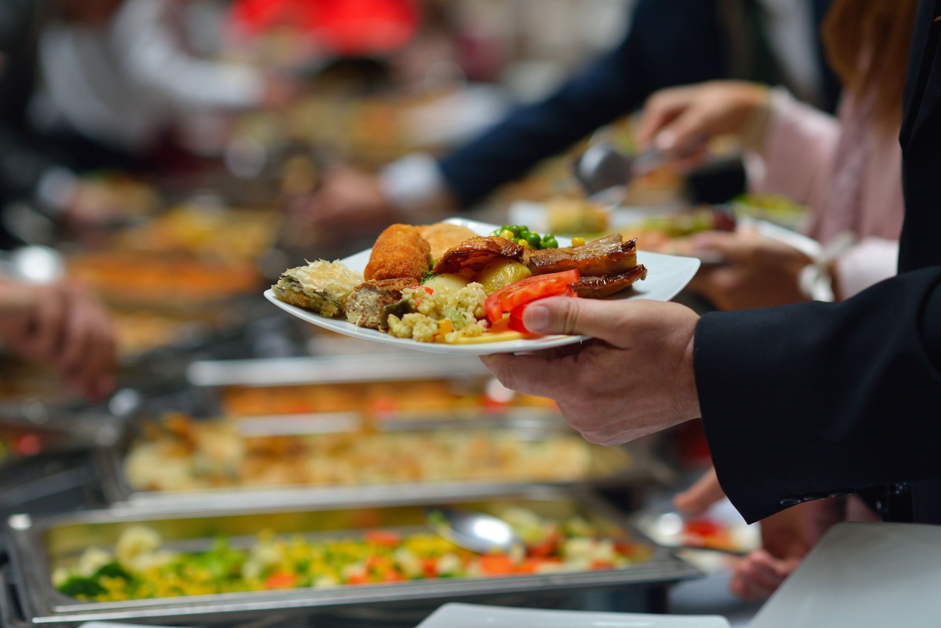 A person is holding a plate of food at a buffet.