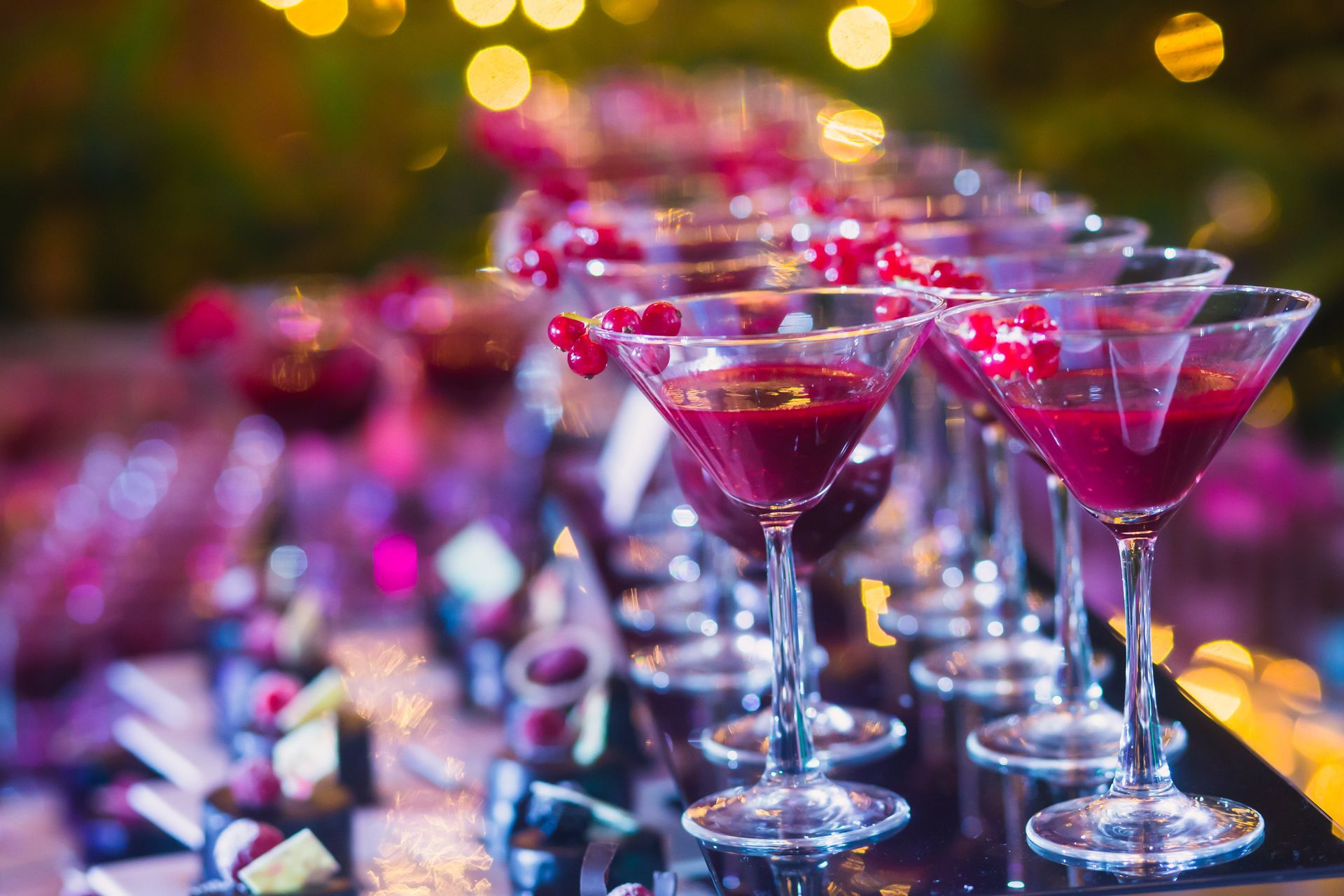 A row of martini glasses filled with red liquid on a table.