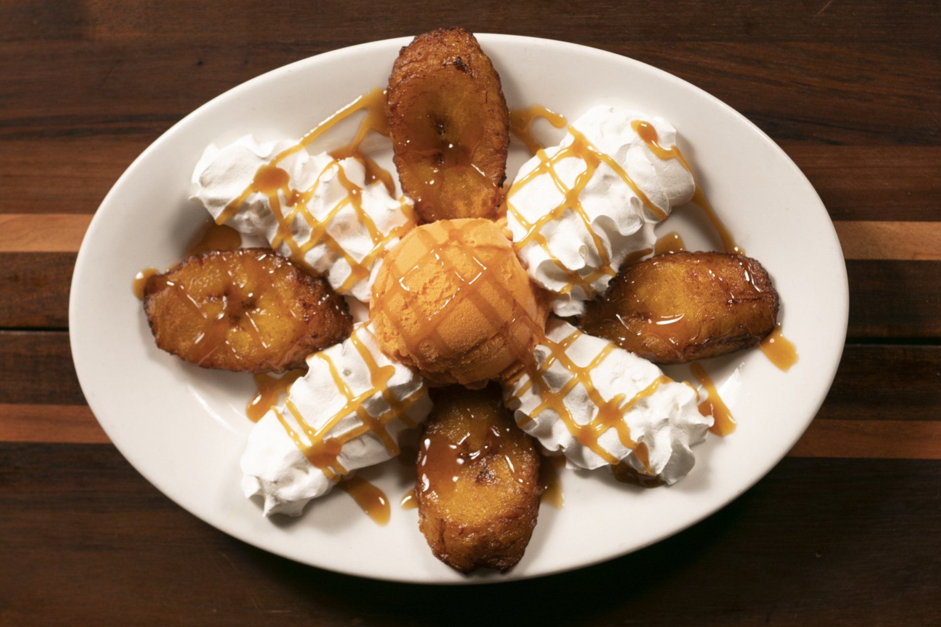Plate with fried bananas, whipped cream, caramel drizzle, and cake.
