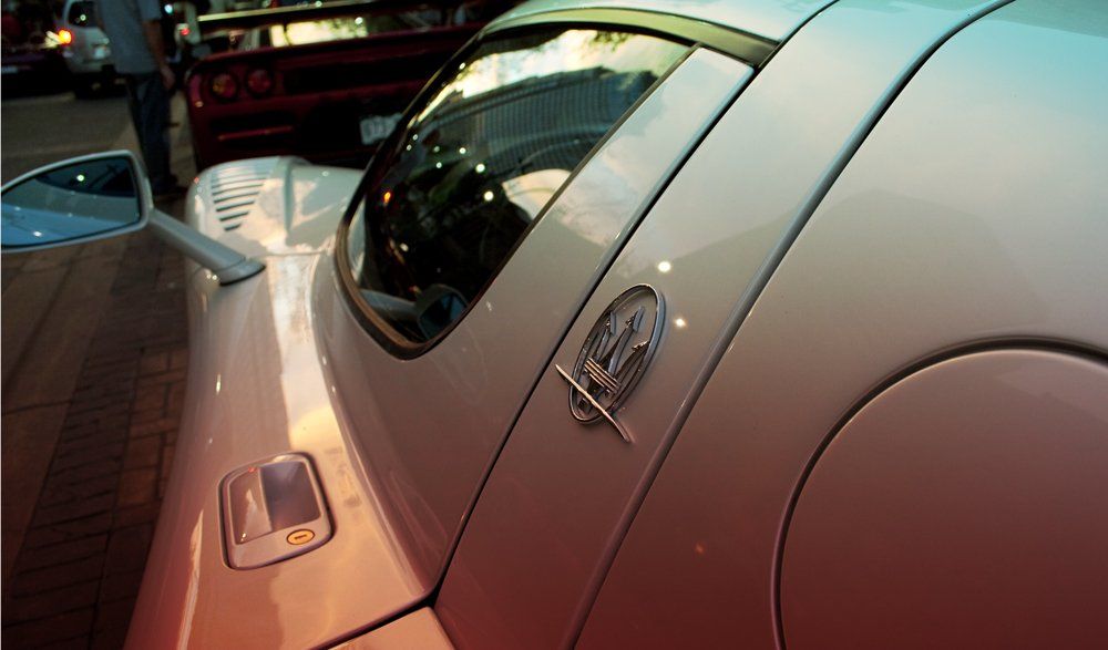 A silver car with a maserati logo on the side is parked on a red carpet.