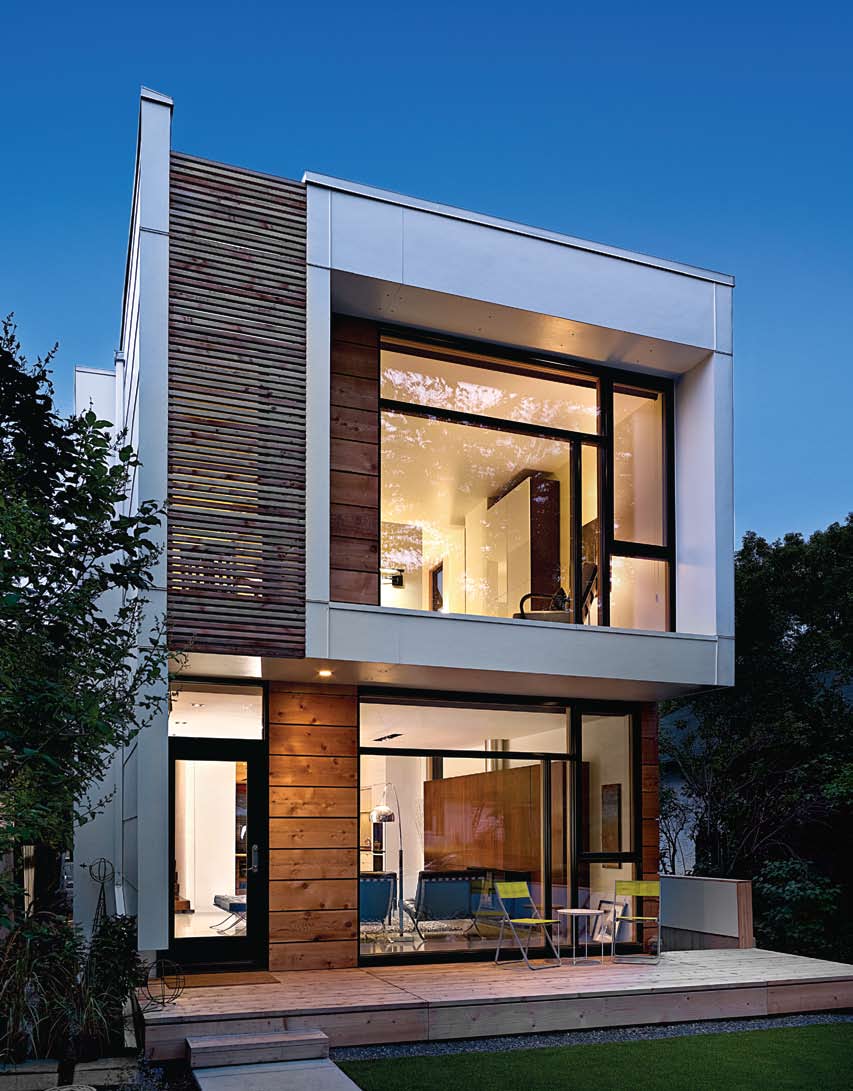 A modern house with a lot of windows is lit up at night