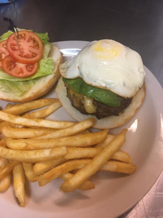 A hamburger with a fried egg and french fries on a plate