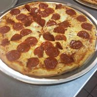 A pepperoni pizza is sitting on top of a metal pan on a table