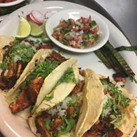 A plate of tacos with a side of salsa on a table
