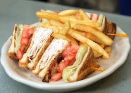A club sandwich with french fries on a plate on a table