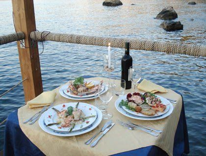Un tavolo apparecchiato con dei piatti a base di pesce e vista del mare