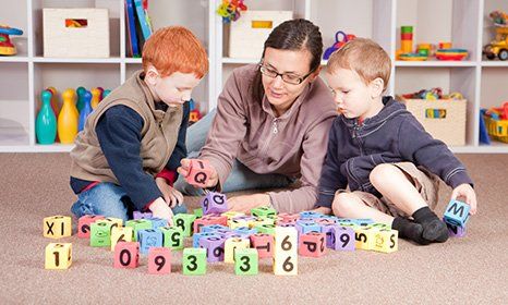 children playing block game with teachers