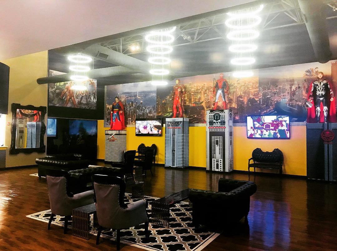Stylish lobby lounge with black chairs, patterned rug, colorful wall art, and bright ceiling lights