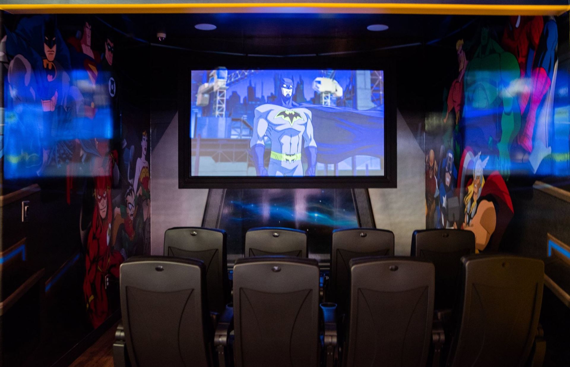 Home theater room with a large screen, six chairs, and colorful wall lighting