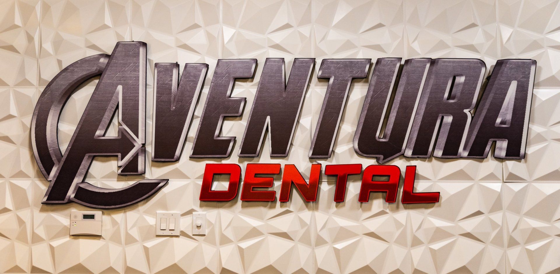 Aventura Dental logo with metallic silver and red text on a beige, textured background