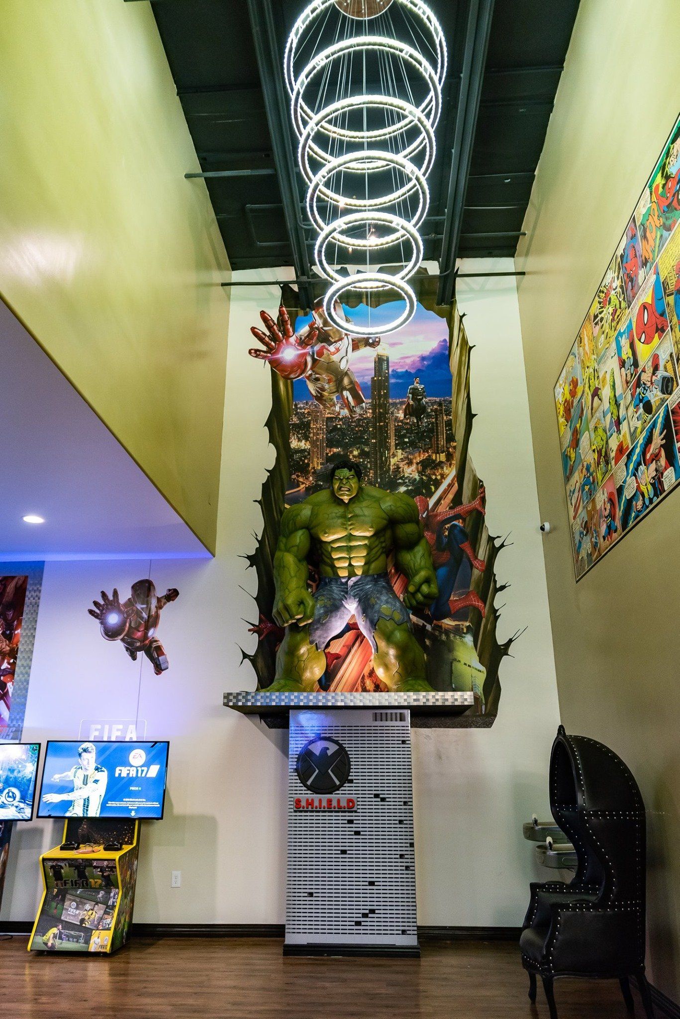 Indoor lobby with a tall decorated Christmas tree and spiral ceiling lights, flanked by colorful wall art and arcade screens