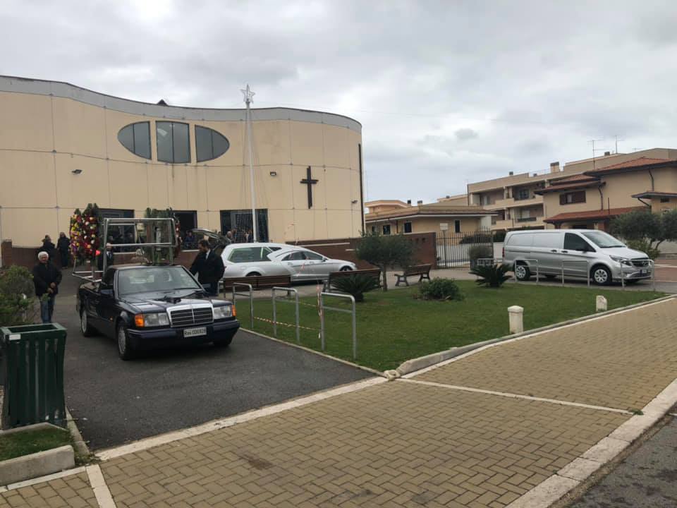 cofano funebre in legno chiaro con composizione floreale
