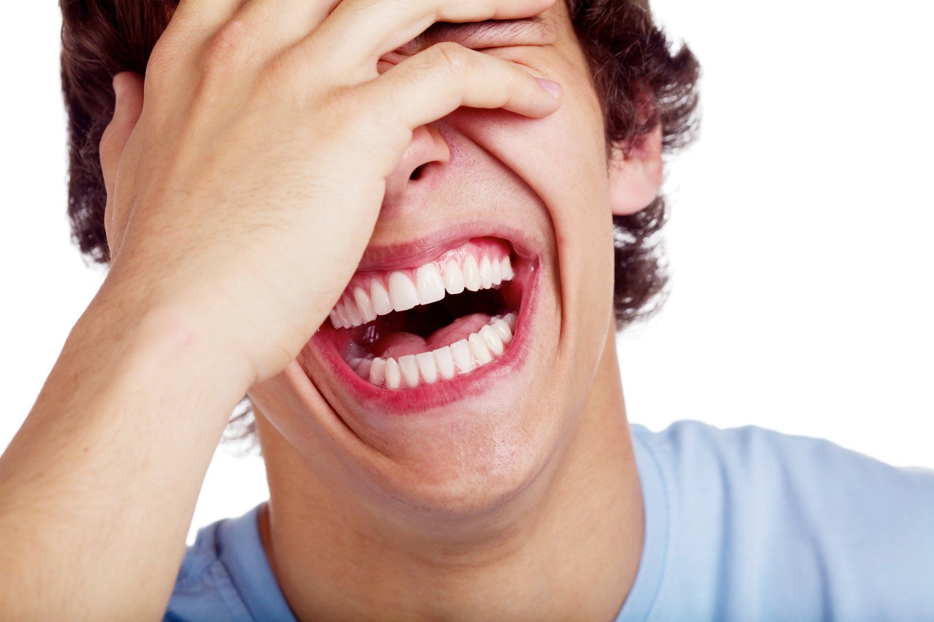 A man is laughing and covering his face with his hand