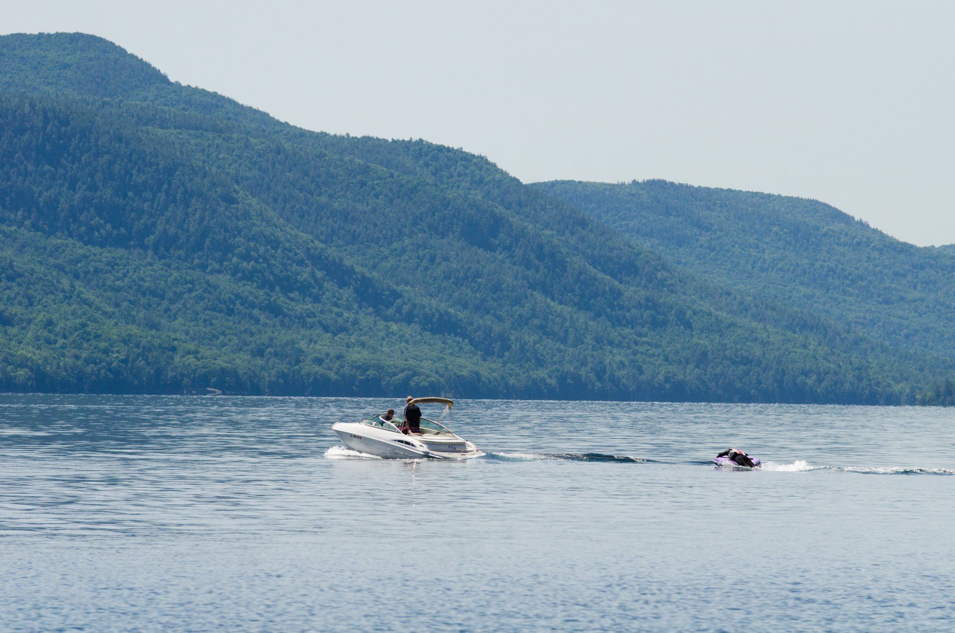 A boat is floating on a lake with mountains in the background.
