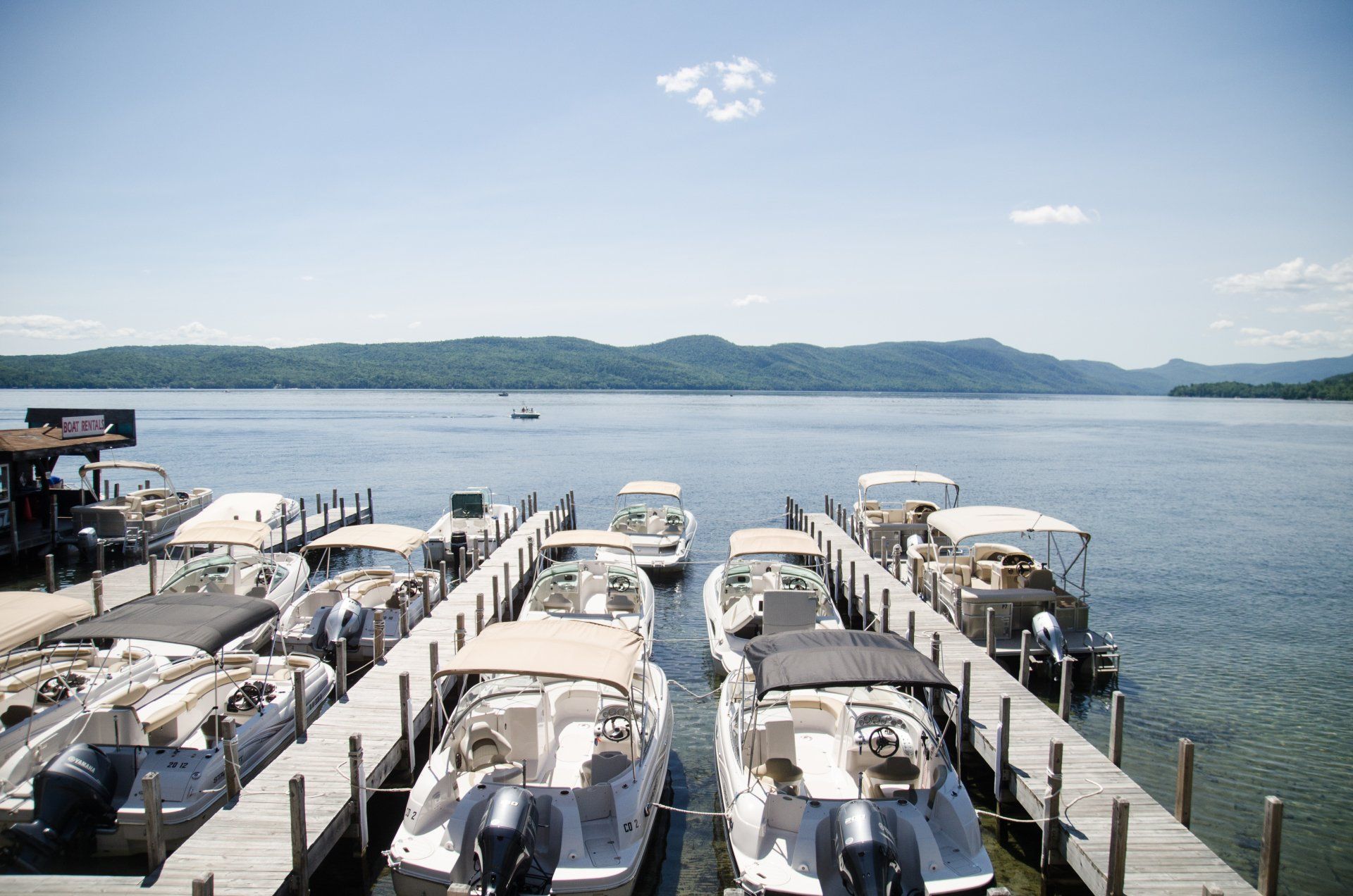 A row of boats are docked at a dock on a lake.