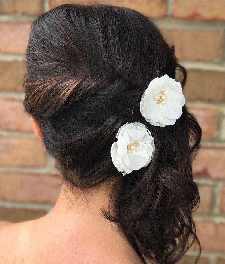 Woman with dark hair styled in an updo, adorned with two white flower hair clips.