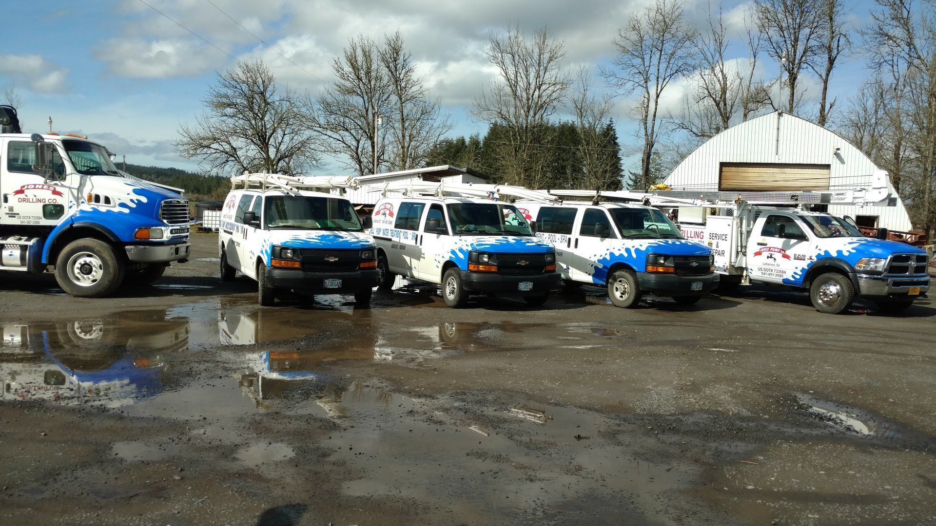 Vehicles with blue and white company logo parked outside; cloudy sky.