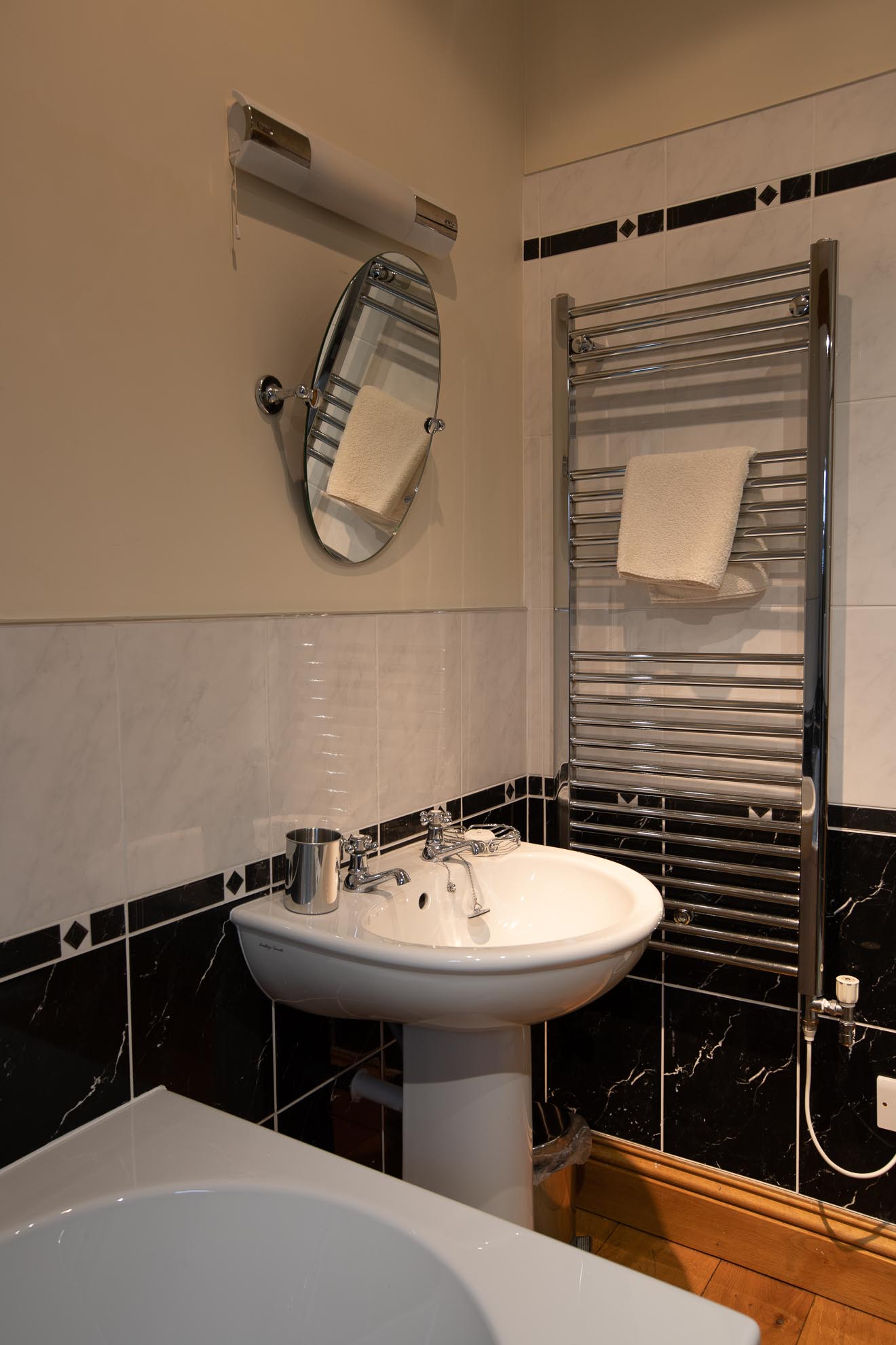 Bathroom interior with a sink, mirror, towel rack, and partially visible bathtub.