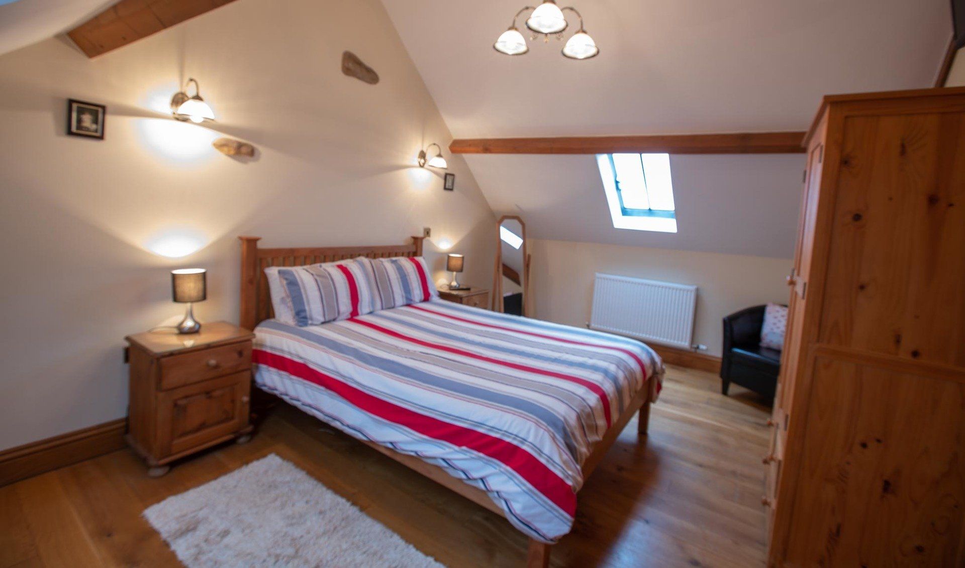 Bedroom with a double bed, wooden furniture, and sloped ceiling with a skylight.