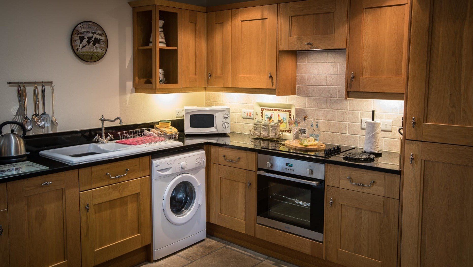 Kitchen with oak cabinets, appliances, black countertops, and a white washing machine.