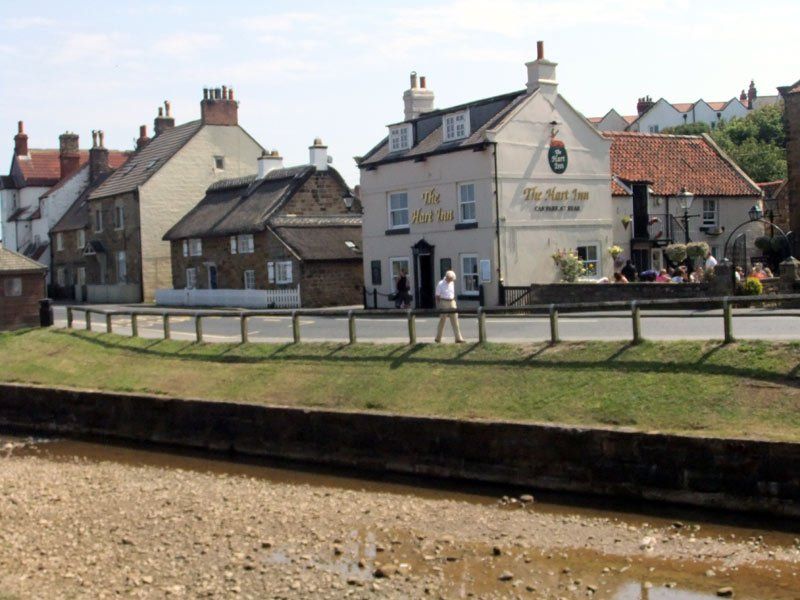 Street scene with buildings, a road, and a person walking. A pub, The Black Lion, is visible.