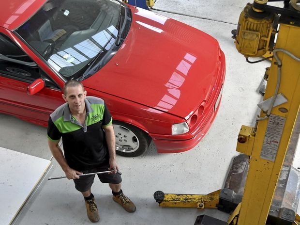 man standing next to red car