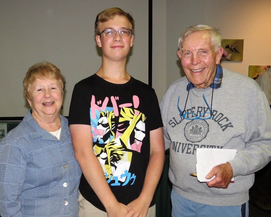 A man wearing a super rock sweatshirt stands between two women and a boy