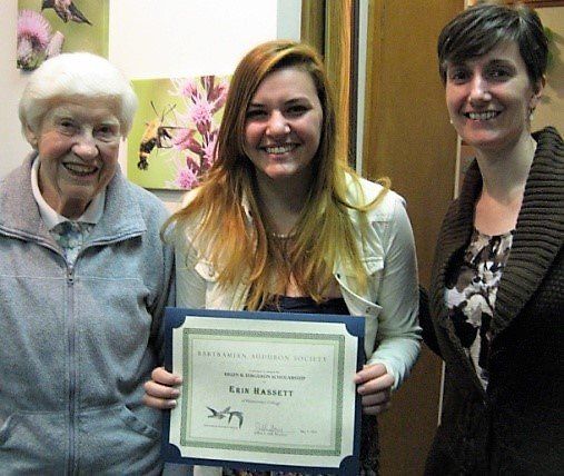 Three women are posing for a picture and one of them is holding a certificate