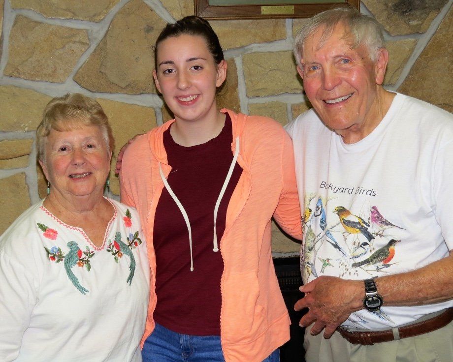 A man wearing a shirt with birds on it poses with two women and a young girl