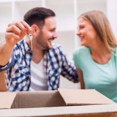 a man and a woman are sitting in a cardboard box holding keys .