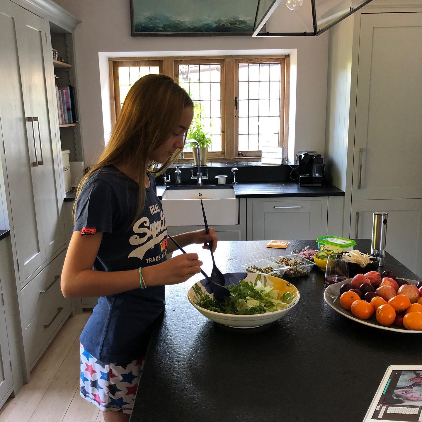 girl tossing salad leaves in newly installed kitchen