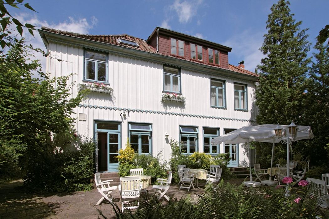 Ein großes weißes Haus mit einer Terrasse und Stühlen davor.