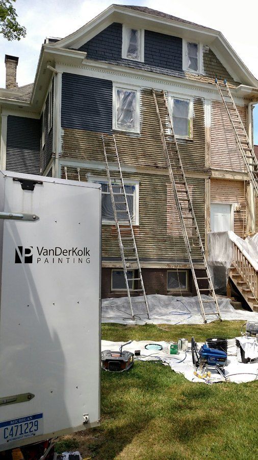 A white truck is parked in front of a house being painted.
