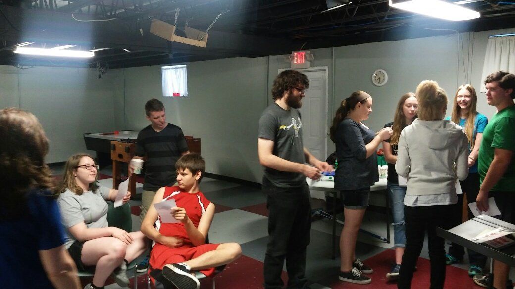 A group of people are standing in a room talking to each other.