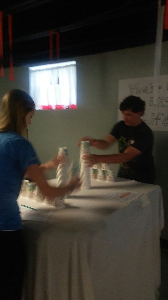 A man and a woman are standing around a table with cups on it.