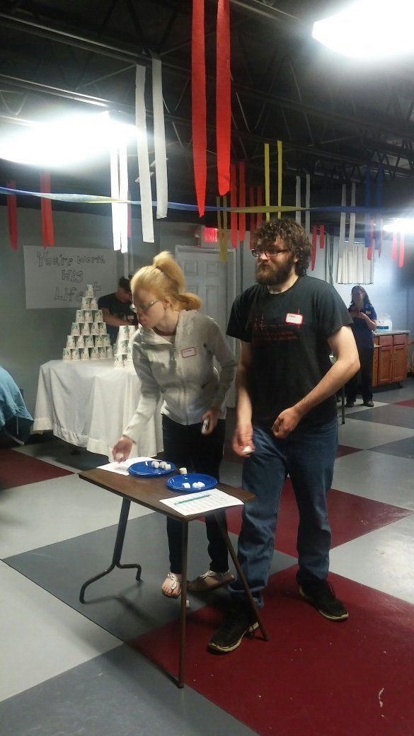 A man and a woman are standing next to a table in a room.