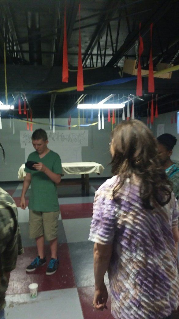 A group of people are standing in a room looking at a tablet.