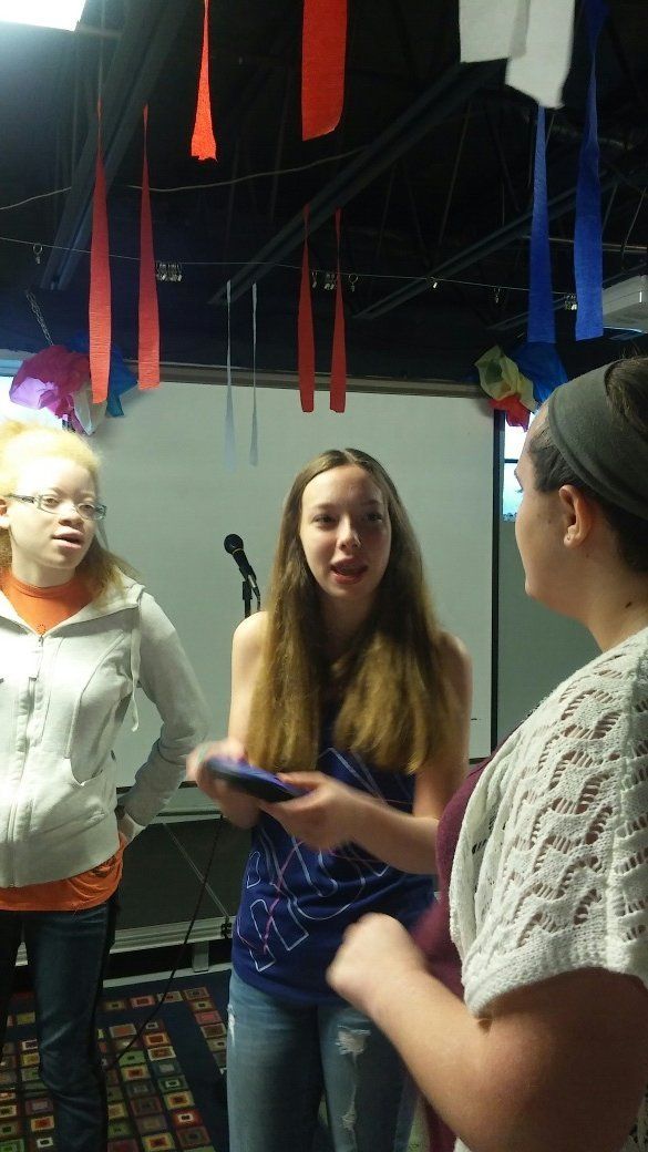 A group of girls are standing in a room with ribbons hanging from the ceiling.